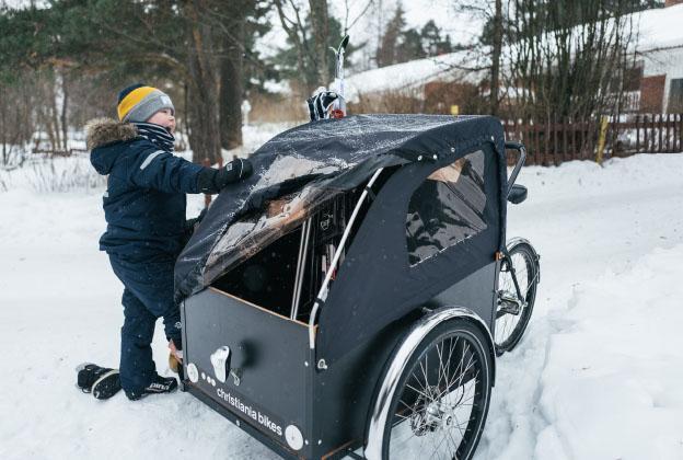 Lapsi lumessa laatikkopyörän kanssa.