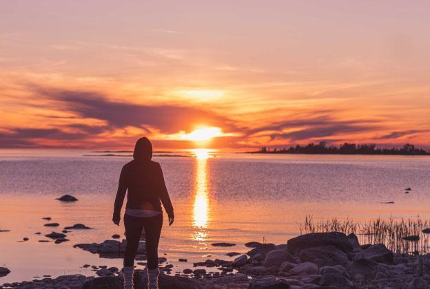 Ihminen rannalla auringonlaskussa.